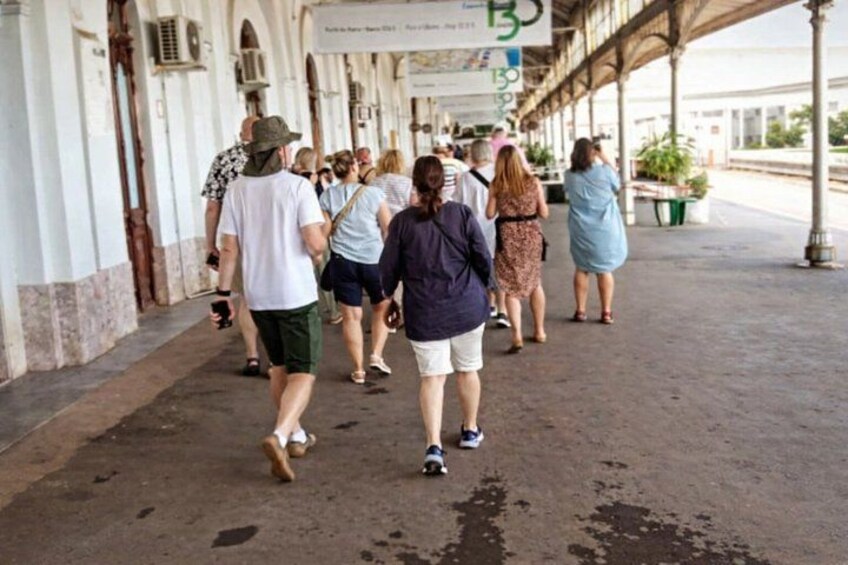 A group of people walking along a covered walkway with columns and signs. 5