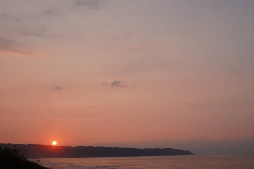 A sunset over a body of water with a distant landmass. 3
