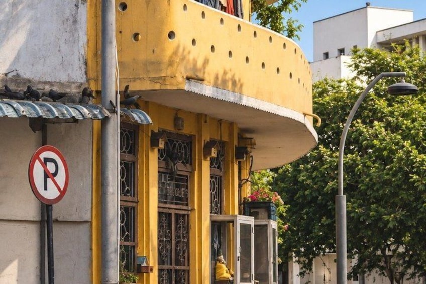 A yellow building with barred windows and a no parking sign. 2