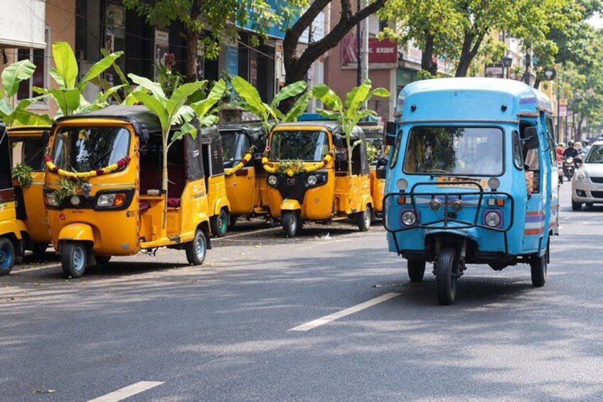 A row of yellow auto-rickshaws parked on the side of a street. 1