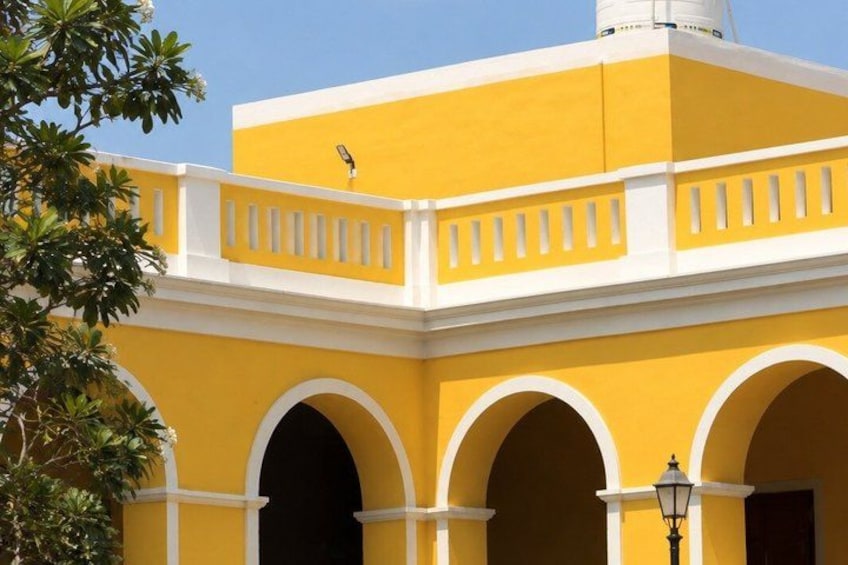 A yellow building with white arches and a balcony. 3