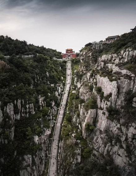 A steep, narrow staircase leading up a rocky mountain, with a traditional building at the top. 1