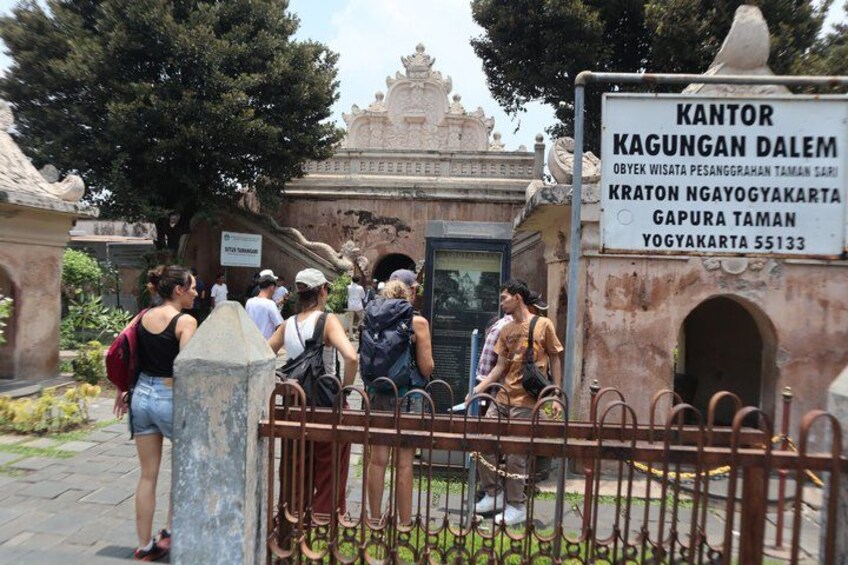 A historical site with visitors, a signboard, and a gate. 3