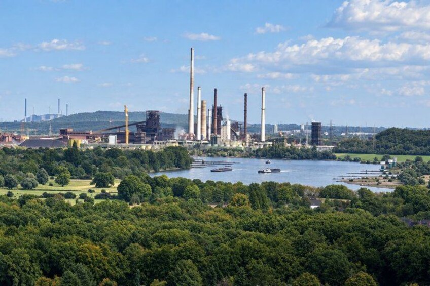 A power plant with tall chimneys, a river, and surrounding greenery. 4