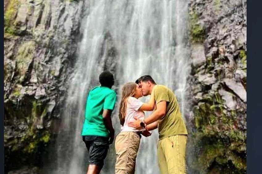 A waterfall with people standing and embracing in front of it. 2