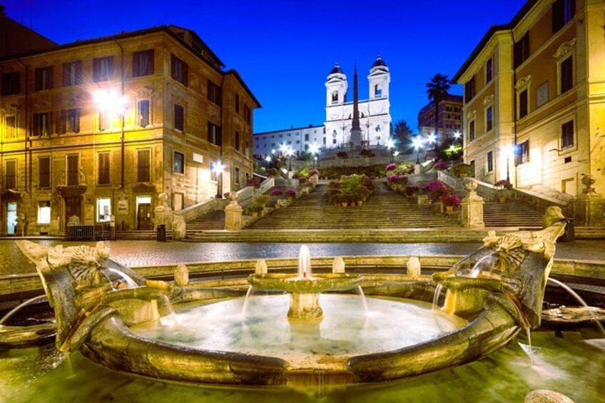 A historic fountain with water jets, surrounded by classical architecture and a grand staircase leading to a church. 4