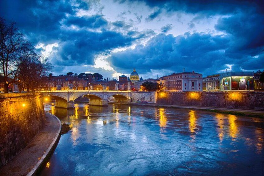 A river with a bridge, a domed building, and illuminated buildings along the riverbank. 2