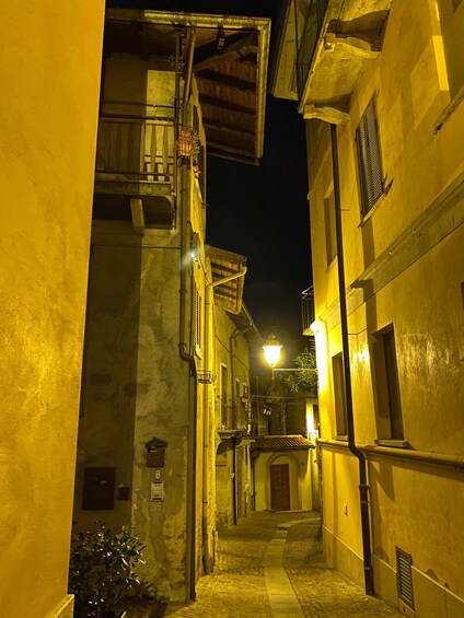 Un callejón estrecho flanqueado por edificios, iluminado por farolas. 3
