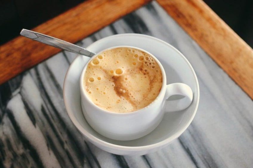 A cup of coffee with a spoon on a saucer, placed on a marble surface. 1