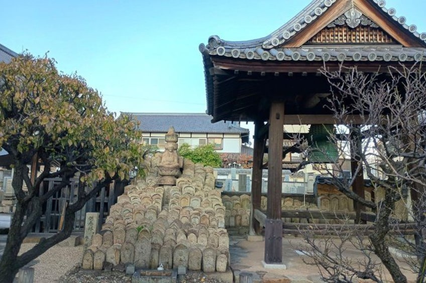 A traditional Japanese pagoda with a tiled roof, surrounded by stone lanterns and a tree. 5