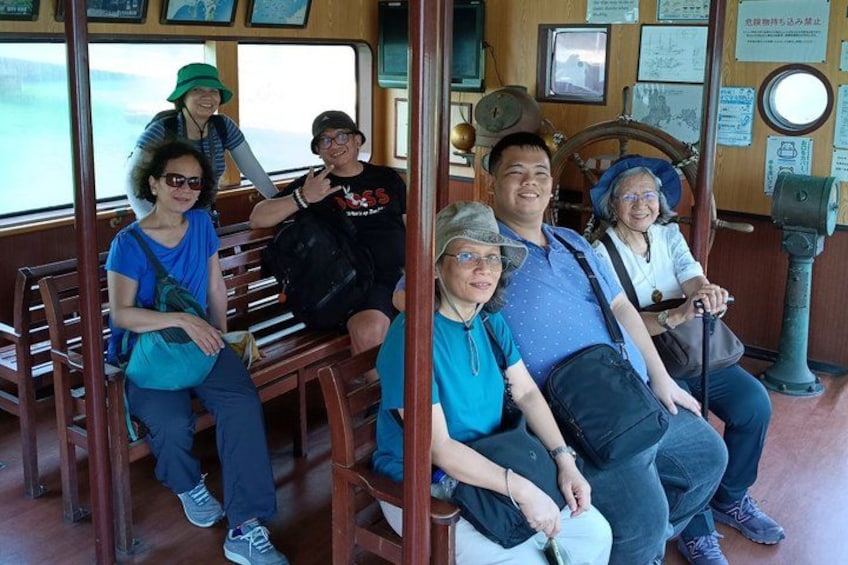 A group of people seated on wooden benches inside a boat. 2