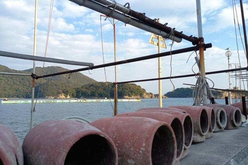 A row of rusted pipes on a boat, with a mountainous landscape in the background. 4