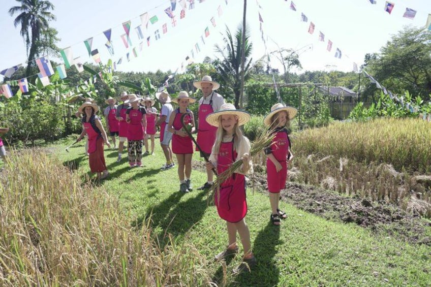 A group of people in red aprons and hats, walking through a grassy area with flags in the background. 1