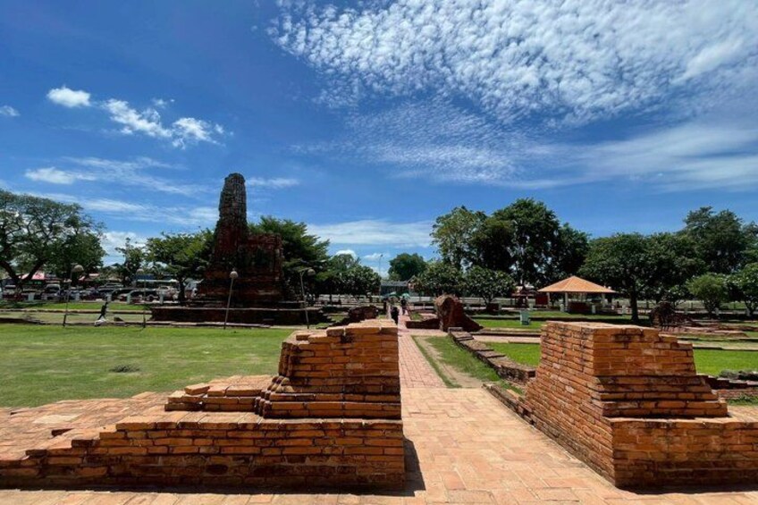 Ancient brick structures, a tall stone monument, and a clear blue sky with scattered clouds. 4
