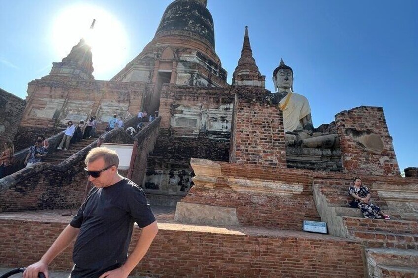 Una estatua grande de Buda, ruinas antiguas de ladrillo y una persona caminando. 5