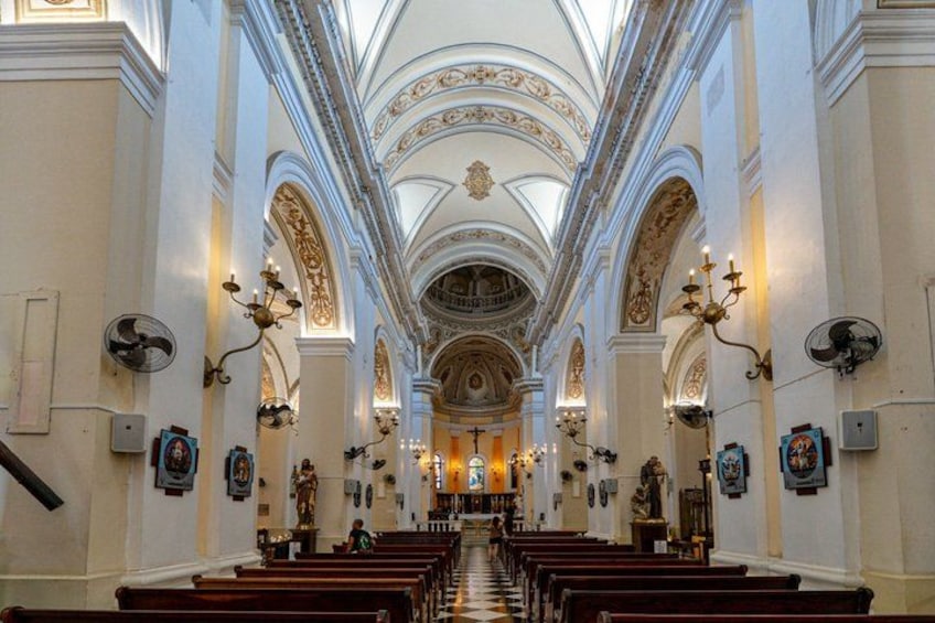 An interior of a church with rows of pews, a high arched ceiling, and religious icons. 5