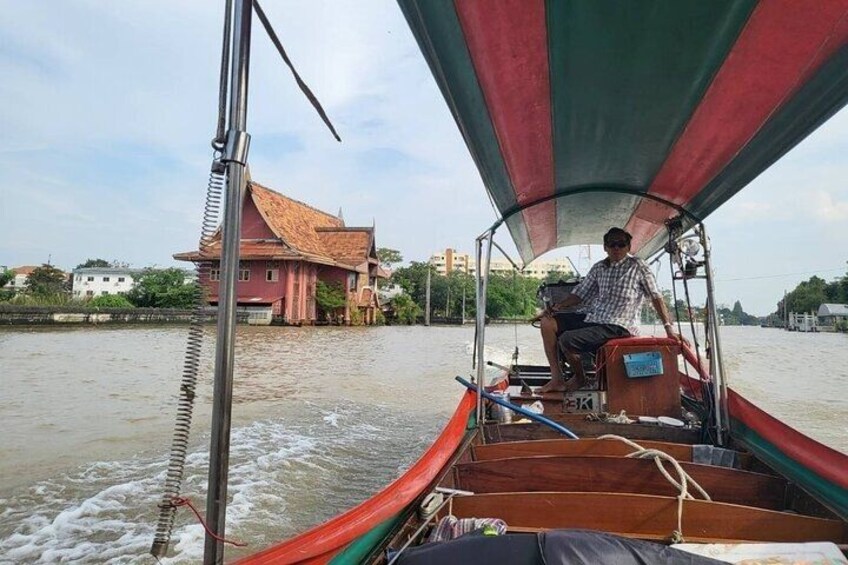 A traditional boat with a person steering, a house with a red roof, and a calm river. 3