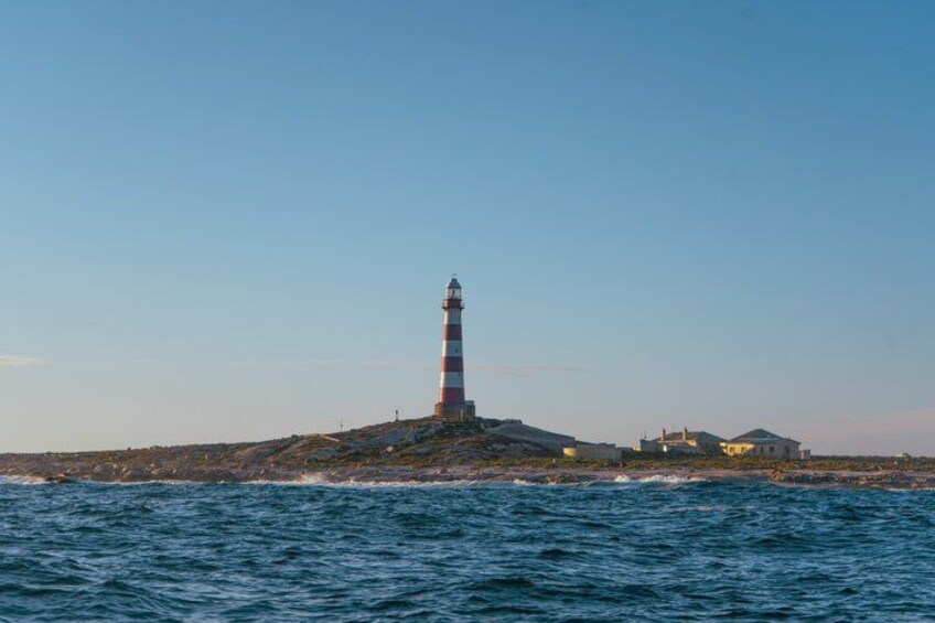 A lighthouse on a rocky island with a clear sky. 5