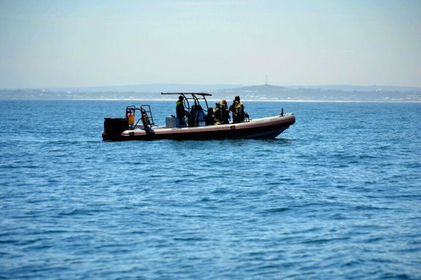 A small boat with people on it, moving across a body of water. 3