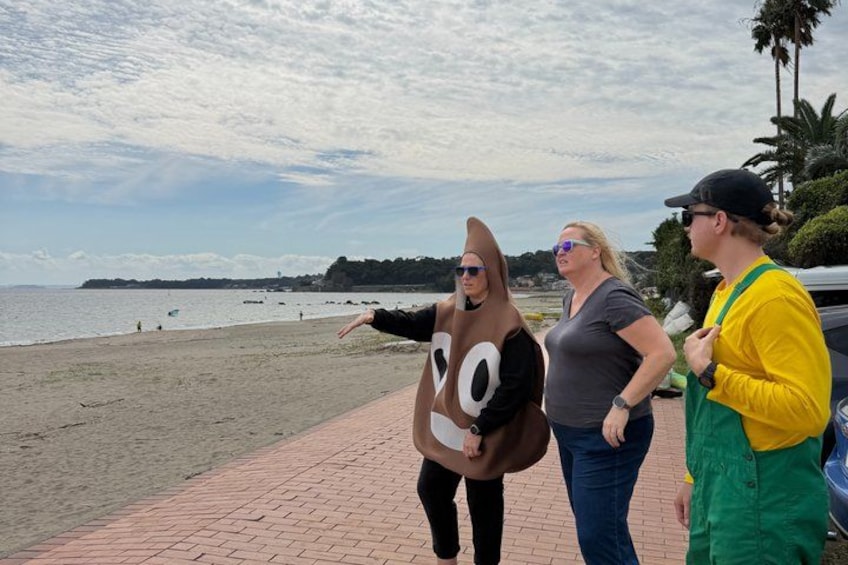 A beach with people, one in a banana costume, and a car parked nearby. 3