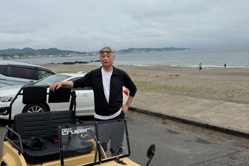 A man standing next to a yellow vehicle with a black seat and a sign that reads 'NEXT CRUISER' on the front. 5