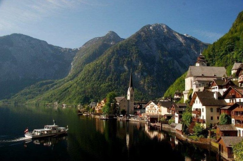A lakeside village with traditional buildings, a church, and mountains in the background. 1