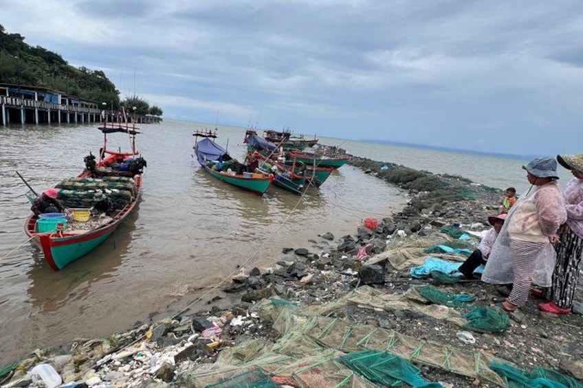 Boats docked at a pier, fishing nets on the shore, and people standing nearby. 5