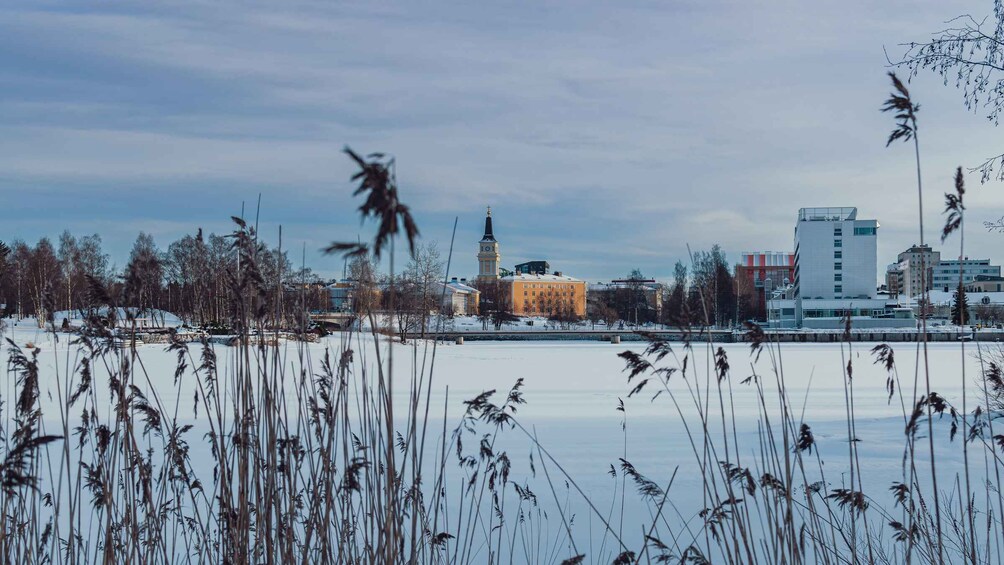 Un lac gelé, avec des roseaux au premier plan, une église dotée d’un clocher et, au loin, des bâtiments modernes. 5