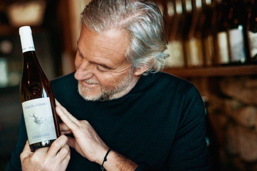 A person holding a bottle of wine with a label that reads 'PORTA VENTO.' 1