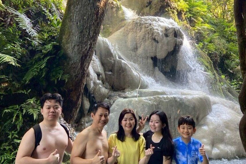 A group of people posing in front of a waterfall surrounded by lush greenery. 3