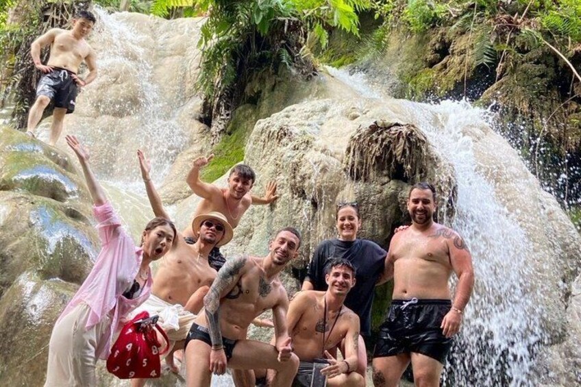 A group of people enjoying a waterfall in a natural setting. 5