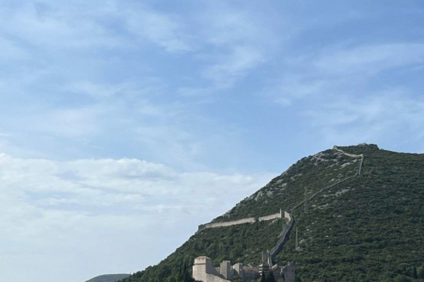 A mountainous landscape with a winding road and a stone structure at the base. 5