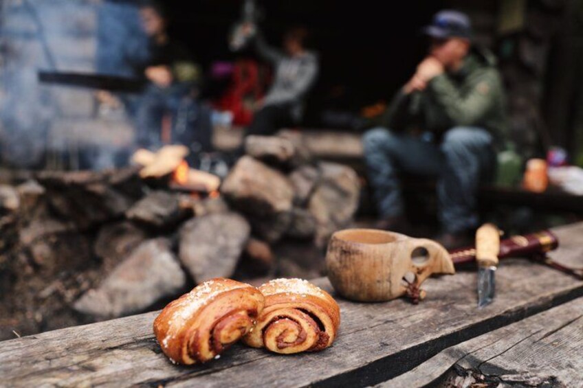 A rustic wooden table with a rolled pastry, a wooden mug, and a wooden spoon. 2