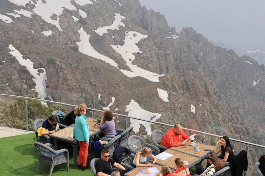 People sitting at tables with a mountainous landscape in the background. 5