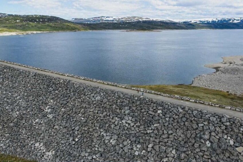 A rocky shoreline with a calm lake and distant mountains. 1