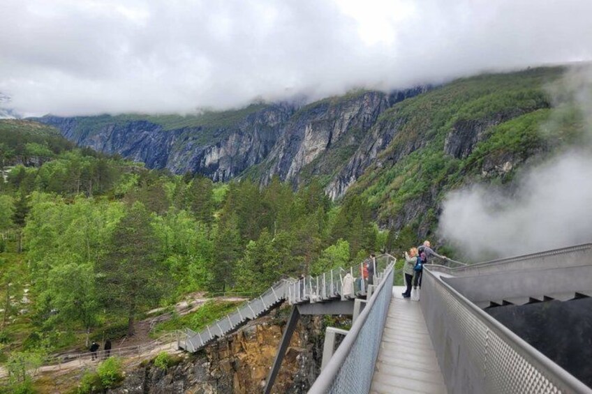 A suspension bridge over a gorge with steep cliffs and lush greenery. 5