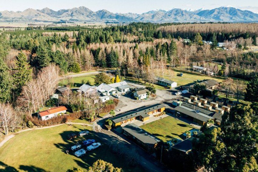 An aerial view of a residential area with houses, a parking lot, and a forested area with mountains in the background. 3