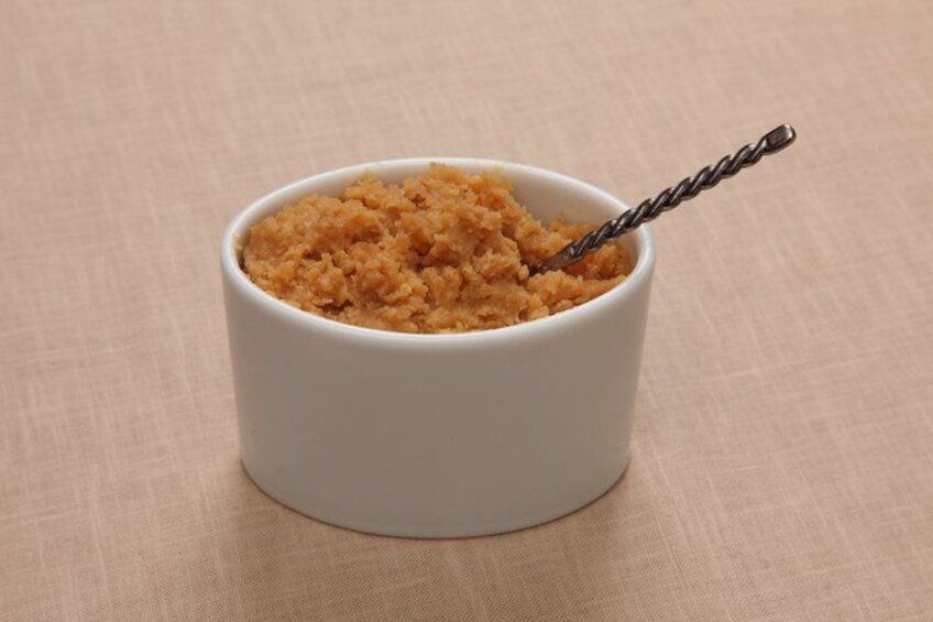 A white bowl filled with brown granules and a twisted metal spoon. 3