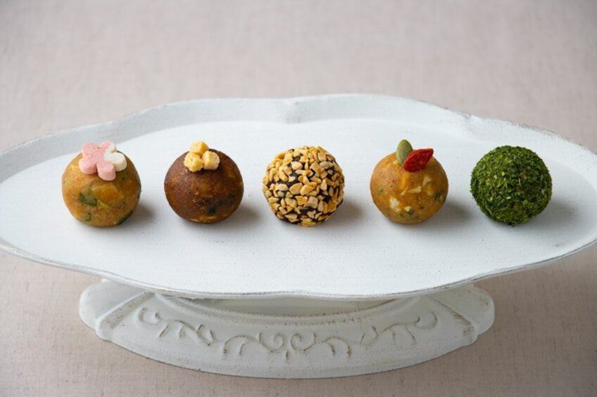 A white plate with five round food items, each with different toppings. 1