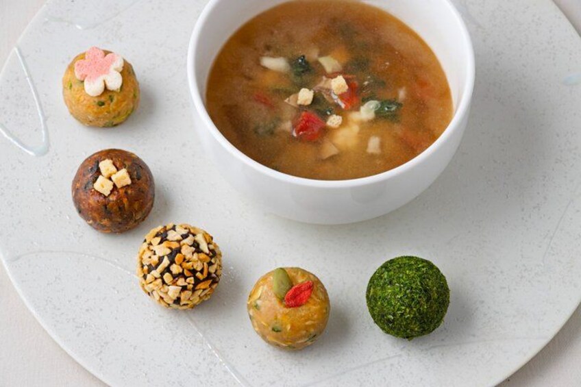 A bowl of soup with various dumplings on a plate. 5