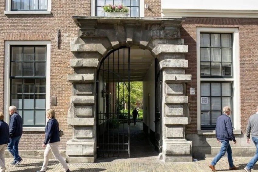 A stone archway leading to a building entrance, with people walking by. 4