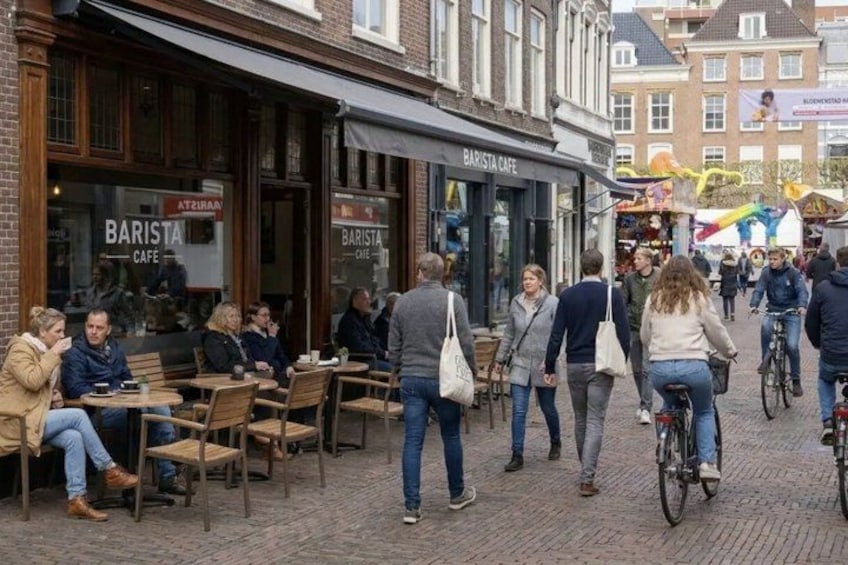 A street with outdoor seating at a cafe, pedestrians, and cyclists. 3