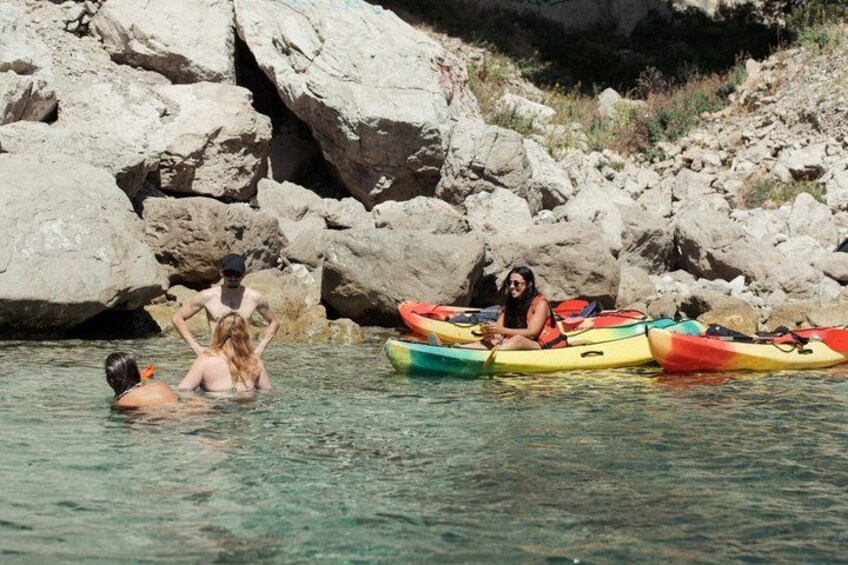 People kayaking in a rocky coastal area with clear water. 5