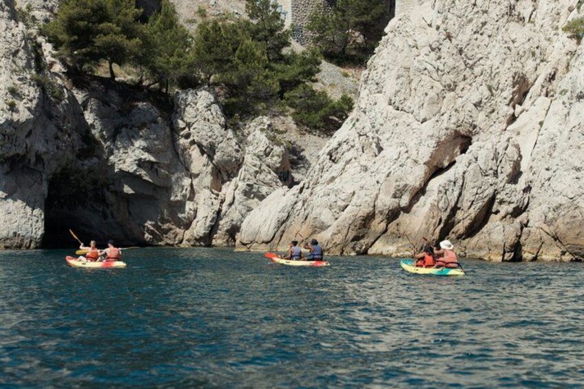 Three kayaks navigating a narrow waterway between rocky cliffs. 2