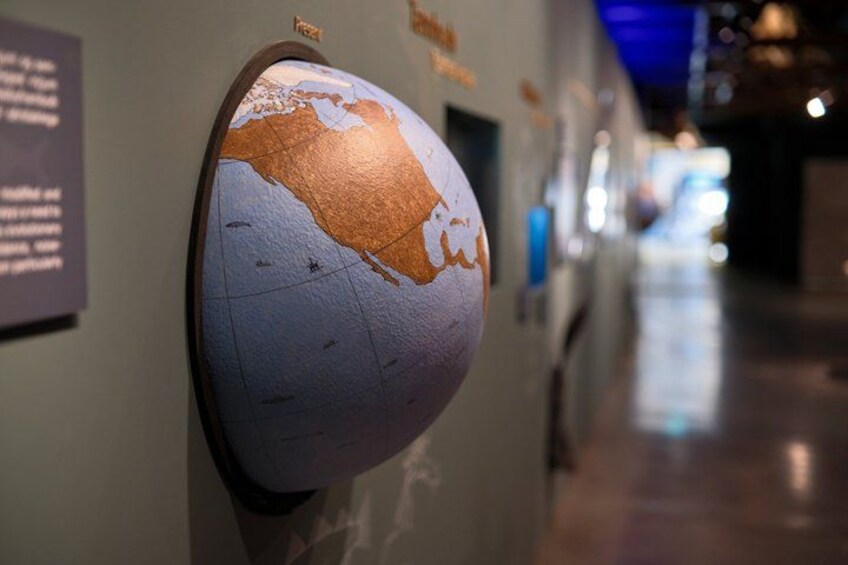 A globe with a cracked surface, mounted on a wall with informational plaques. 5