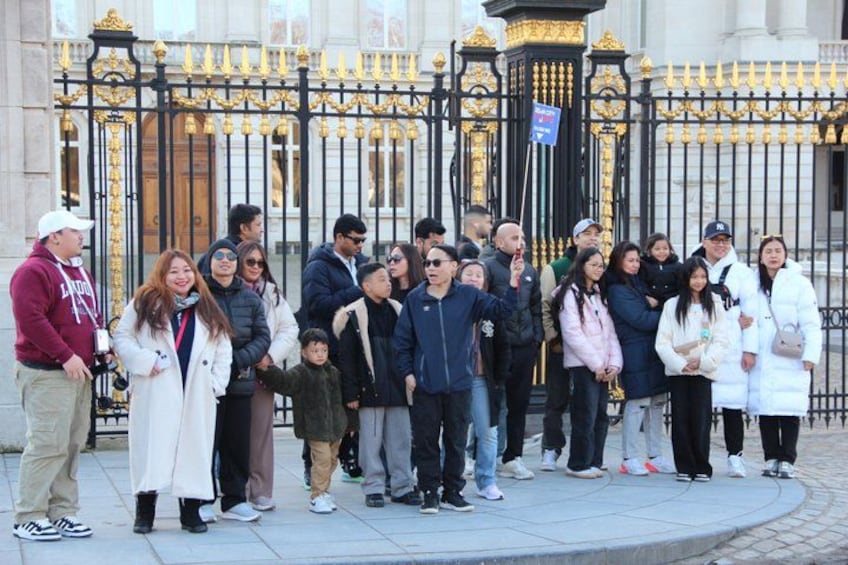 A group of people standing in front of a black and gold gate. 5
