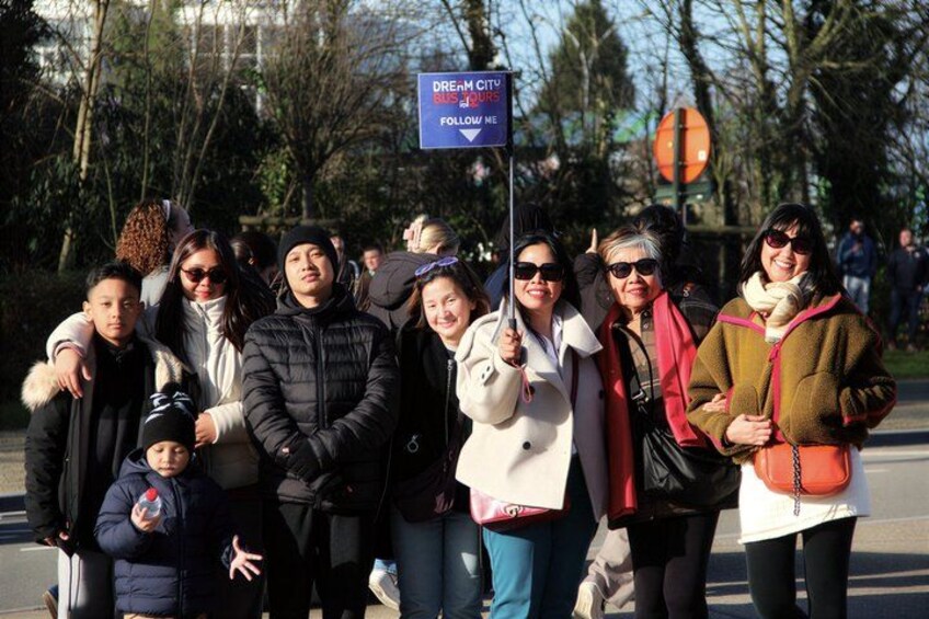 A group of people standing on a street with a sign that reads 'DREN CITY FOLLOW ME'. 3
