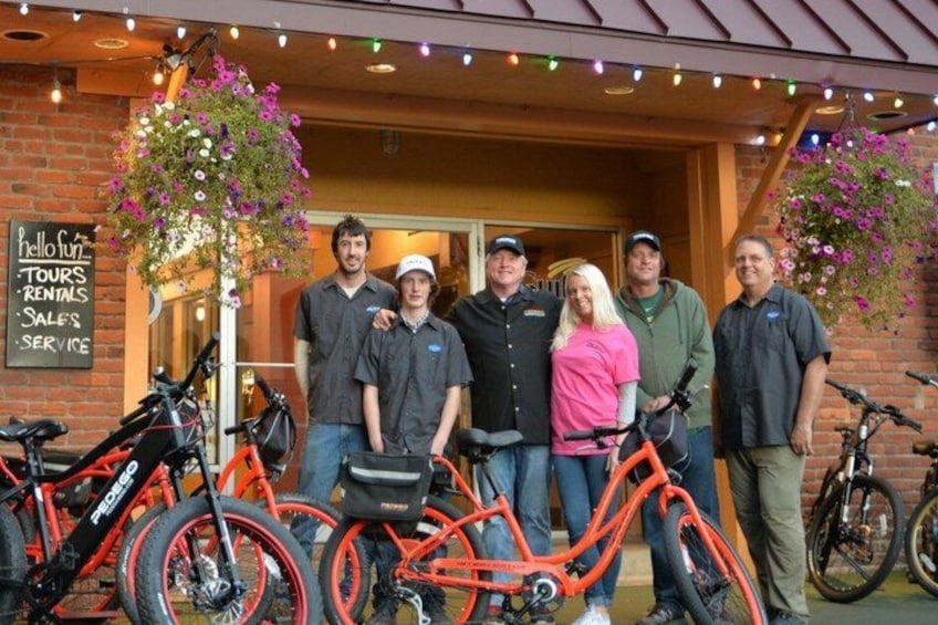 A group of people standing in front of a building with bicycles and a sign that reads 'hello fun tours rentals sales service.' 5