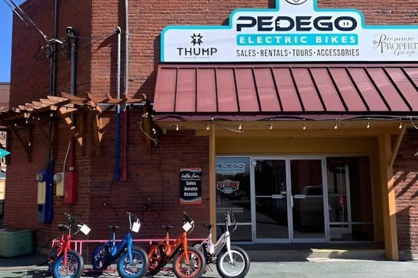 A brick building with a sign for Pedego Electric Bikes. 4