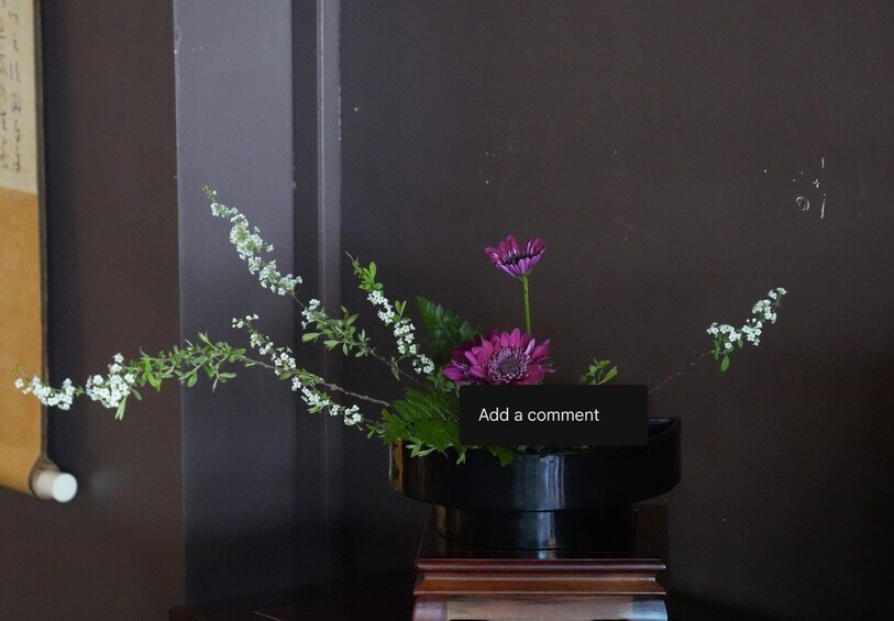 En vase med blomster og en kommentarboks på et bord. 2